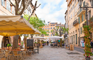 cosa vedere tra provenza e camargue - un violetto della cittadina di Grasse, Provenza con bar ed ombrelloni bianchi